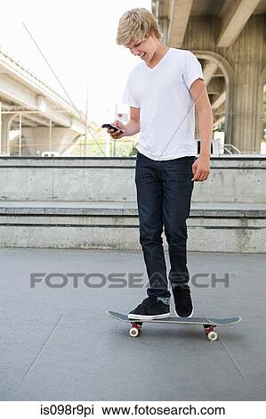Teenage boy on skateboard with cellphone View Large Photo Image Stock Image - Teenage boy on skateboard with cellphone. Fotosearch