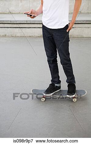 Teenage boy on skateboard with cellphone View Large Photo Image Stock Photo - Teenage boy on skateboard with cellphone. Fotosearch