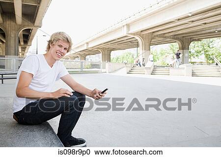Teenage boy with cellphone in skatepark View Large Photo Image Stock Image - Teenage boy with cellphone in skatepark. Fotosearch