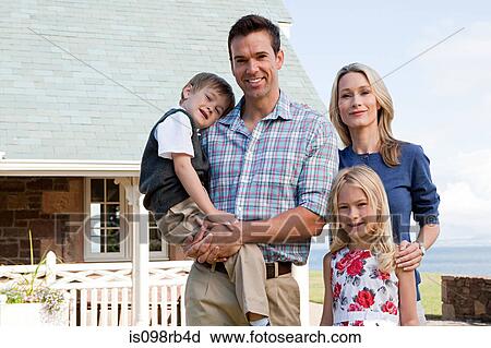Stock Image - Family outside holiday home. Fotosearch