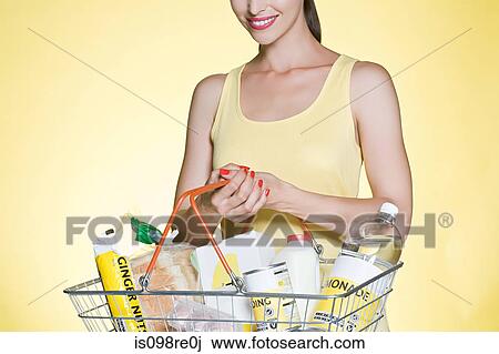 Stock Image - Woman with basic groceries in basket. Fotosearch