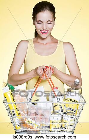 Stock Photograph - Woman with basic groceries in basket. Fotosearch
