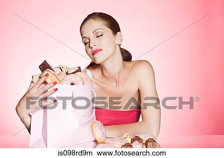 Picture - Young woman with bag of cakes and donuts. Fotosearch