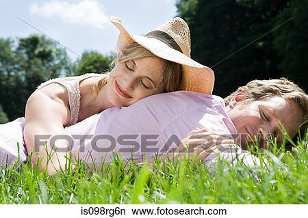 Picture - Couple lying in field. Fotosearch