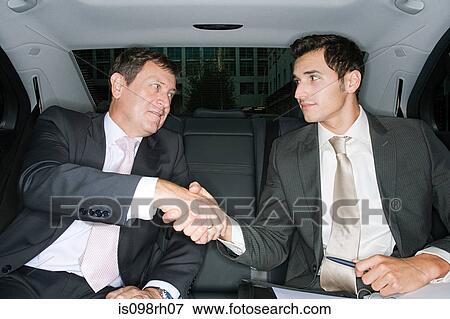 Businessmen shaking hands in a car View Large Photo Image Stock Photo - Businessmen shaking hands in a car. Fotosearch