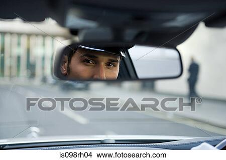 Chauffeur looking in rear view mirror View Large Photo Image Picture - Chauffeur looking in rear view mirror. Fotosearch