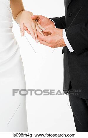 Groom placing a ring on brides finger View Large Photo Image Stock Image - Groom placing a ring on brides finger. Fotosearch