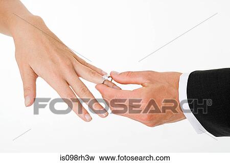 Groom placing ring on brides finger View Large Photo Image Stock Photo - Groom placing ring on brides finger. Fotosearch
