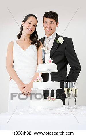 Newlyweds standing by wedding cake View Large Photo Image Stock Image - Newlyweds standing by wedding cake. Fotosearch