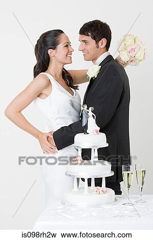 Newlyweds standing near wedding cake View Large Photo Image Stock Photo - Newlyweds standing near wedding cake. Fotosearch