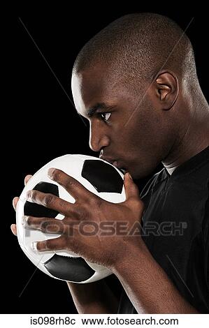 Stock Image - Footballer kissing a football. Fotosearch