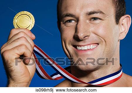 Male athlete holding a medal View Large Photo Image Stock Image - Male athlete holding a medal. Fotosearch