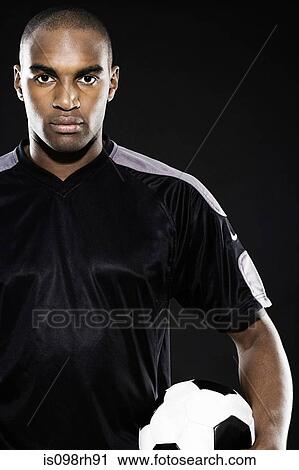Serious footballer holding a ball View Large Photo Image Stock Image - Serious footballer holding a ball. Fotosearch