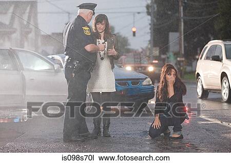 Stock Image - Police officer and young women at scene of accident. Fotosearch