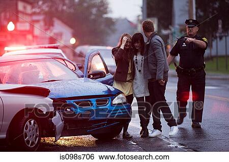 Stock Photograph - Young people and police officer at scene of car crash. Fotosearch