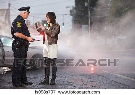 Stock Photo - Young woman and police officer at scene of crash. Fotosearch