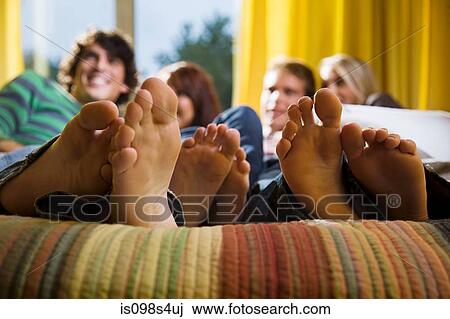 Stock Image - Friends on bed with bare feet. Fotosearch