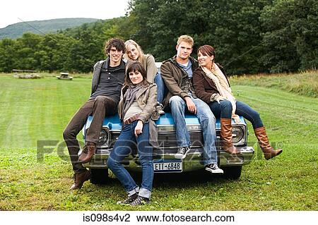Stock Image - Friends sitting on a car. Fotosearch