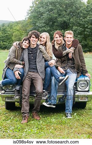 Stock Photo - Friends sitting on a car. Fotosearch