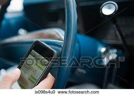 Stock Image - Person driving and using cellphone. Fotosearch