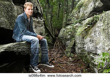 Picture - Teenage boy sitting on rock. Fotosearch
