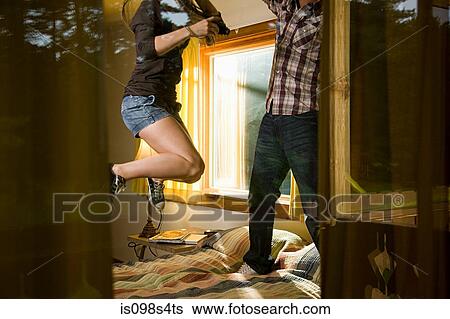Stock Photograph - Young couple jumping on bed. Fotosearch