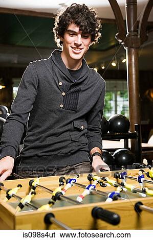 Stock Photograph - Young man playing table football. Fotosearch