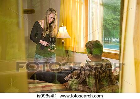 Stock Image - Young woman photographing boyfriend. Fotosearch