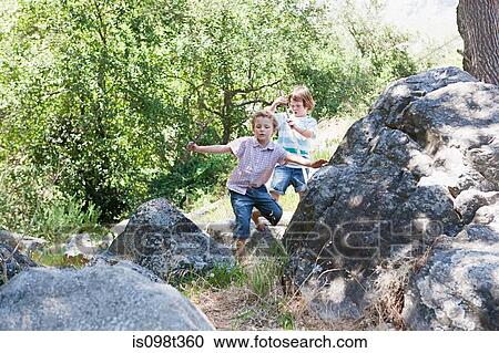 Boys walking through rocks View Large Photo Image Stock Image - Boys walking through rocks. Fotosearch