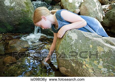 Stock Photo - Girl on rock by river. Fotosearch