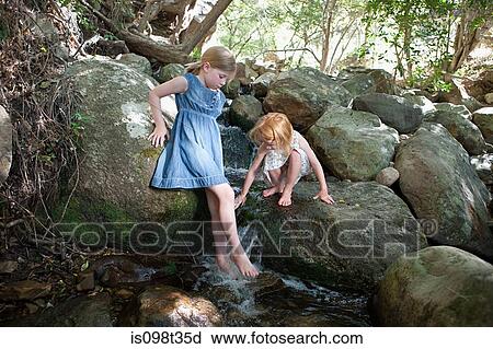 Stock Image - Girls on rock by river. Fotosearch