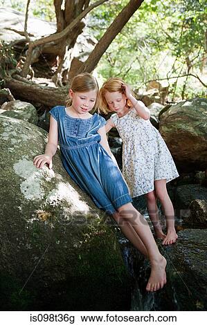 Stock Image - Girls on rock by river. Fotosearch
