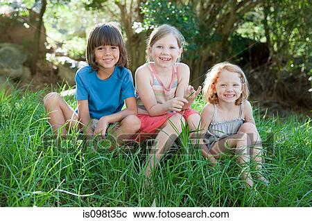 Stock Image - Three children sitting on grass. Fotosearch