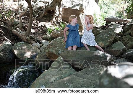Two girls on rocks by river View Large Photo Image Picture - Two girls on rocks by river. Fotosearch
