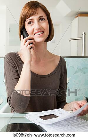 Stock Image - Woman on telephone with bills. Fotosearch