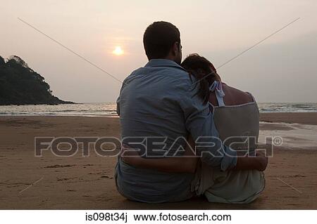 Couple sitting on beach at sunset View Large Photo Image Stock Image - Couple sitting on beach at sunset. Fotosearch