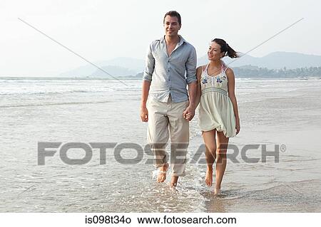 Picture - Couple walking in the sea. Fotosearch