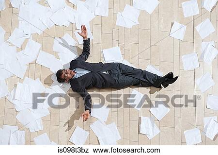 Businessman lying on floor with papers View Large Photo Image Stock Photo - Businessman lying on floor with papers. Fotosearch