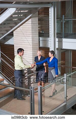 Businesspeople shaking hands on stairwell View Large Photo Image Stock Image - Businesspeople shaking hands on stairwell. Fotosearch