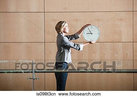 Picture - Businesswoman holding clock. Fotosearch