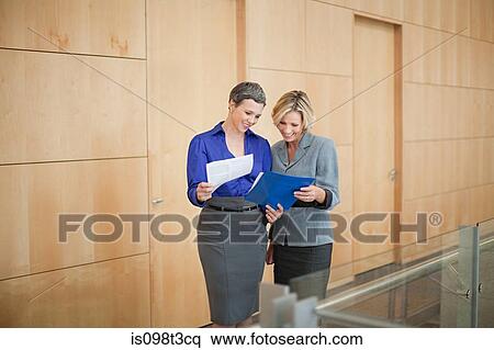 Businesswomen looking at paperwork View Large Photo Image Stock Photography - Businesswomen looking at paperwork. Fotosearch