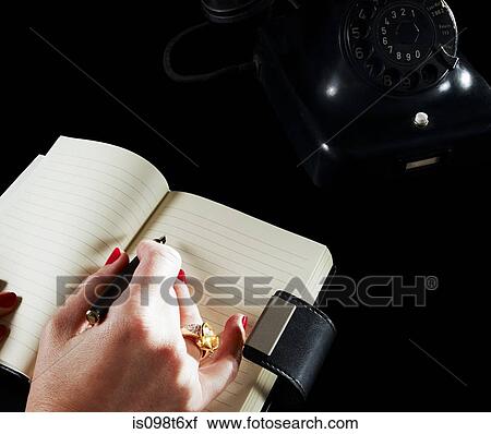 Woman writing in notebook by telephone View Large Photo Image Stock Image - Woman writing in notebook by telephone. Fotosearch