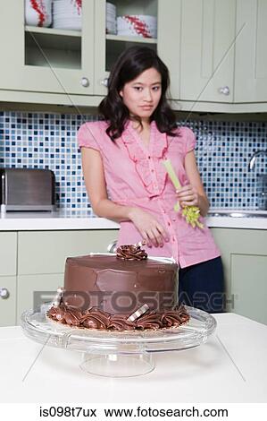 Young woman eating celery, watching chocolate cake View Large Photo Image Stock Photo - Young woman eating celery, watching chocolate cake. Fotosearch
