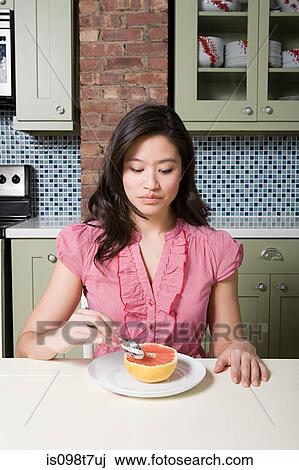 Young woman eating grapefruit View Large Photo Image Stock Image - Young woman eating grapefruit. Fotosearch