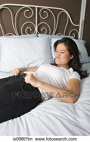 Young woman trying to do up her jeans View Large Photo Image Picture - Young woman trying to do up her jeans. Fotosearch