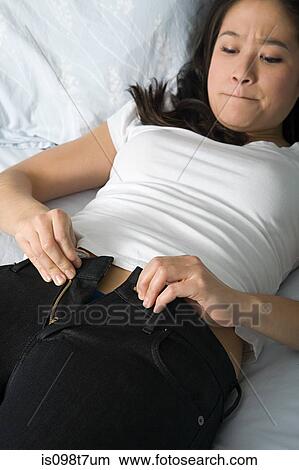 Young woman trying to do up her jeans View Large Photo Image Picture - Young woman trying to do up her jeans. Fotosearch