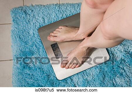 Young woman weighing herself on bathroom scales View Large Photo Image Stock Photography - Young woman weighing herself on bathroom scales. Fotosearch