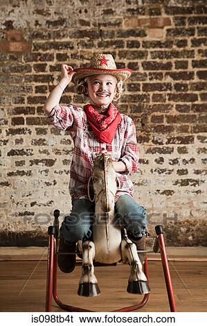Stock Photograph - Young girl dressed as cowgirl with rocking horse. Fotosearch