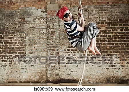 Stock Photo - Young girl dressed up as pirate, climbing rope. Fotosearch