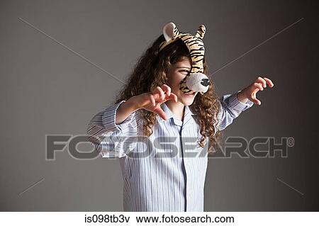 Stock Photo - Young girl wearing tiger mask, roaring. Fotosearch